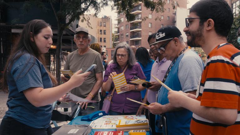 As part of United We Prepare, a student who is also a resiliency fellow helps a neighbor sign up for text alters during a block party event.