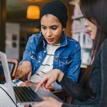 two women looking at computer screen collaborating