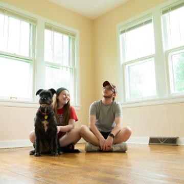 Two people sitting with their dog in a house