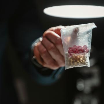 Person holding a small plastic bag of pills and tablets