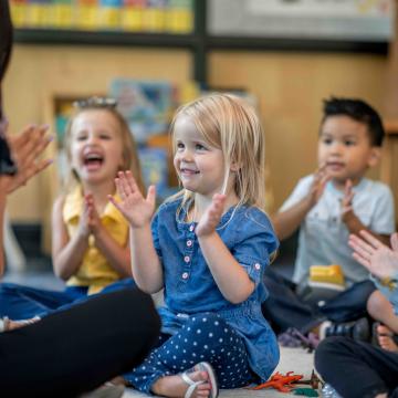 Children in a classroom clapping and playing