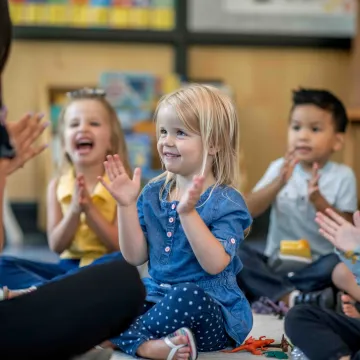 Children in a classroom clapping and playing