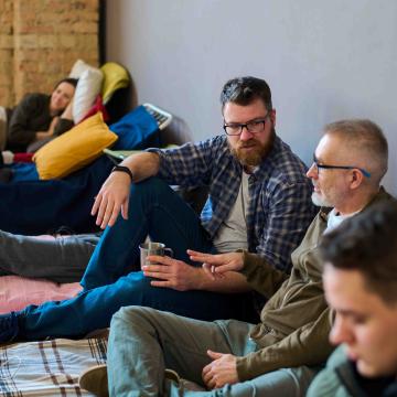 Individuals sitting on the ground at a temporary shelter