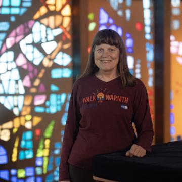 Woman standing in a red shirt that reads "Walk for Warmth"