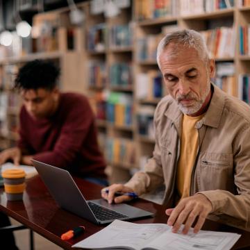 Man working with a computer and a manual
