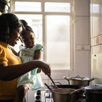Women holding a child cooking on a stove