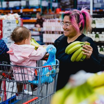 Women in a grocery store with 2 kids, holding bananas