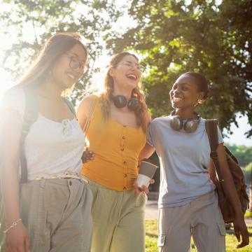 three young women walking together happily