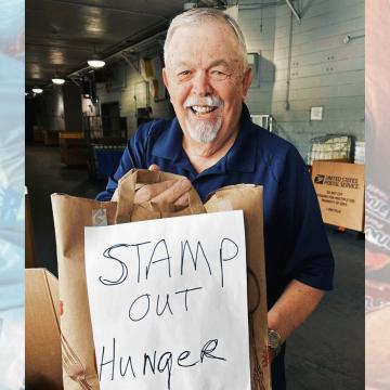 Man with bags of donated items and sign that reads "Stamp out hunger"