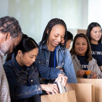 Young adult volunteers packing food items into bags 