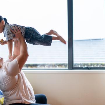 Woman holding a child in the air happily