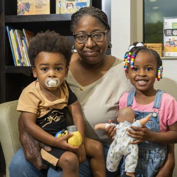 Two children sitting with a woman in a chair.
