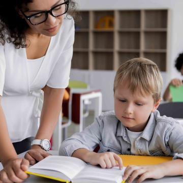 Boy reading at his desk with help