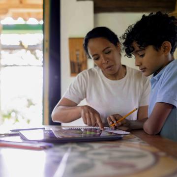 A mother is helping her son with his homework at a table