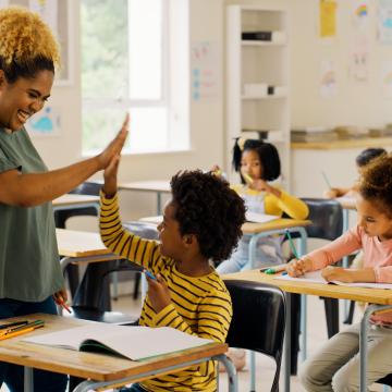 Teacher in a school giving a student a high five