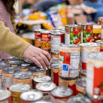 A woman selects canned goods at a food distribution location.