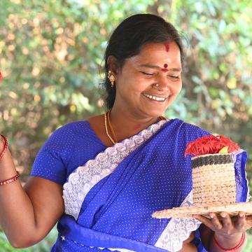 A woman in a blue sari holds woven products