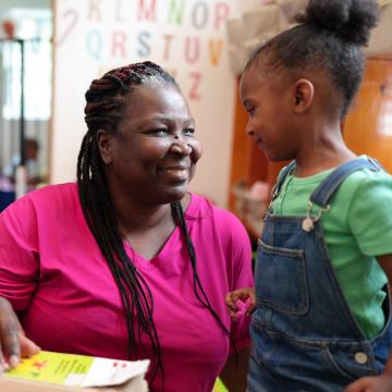 Childcare worker smiling while looking at a child