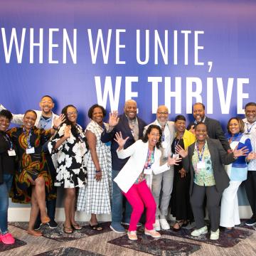 People on a stage under the text, when we unite, we thrive.