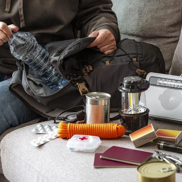 A person stuffing a water bottle in a go bag.