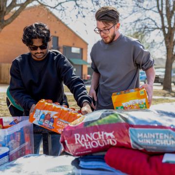 Two men stacking pet food