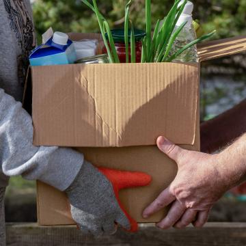 Two people holding a box of food items