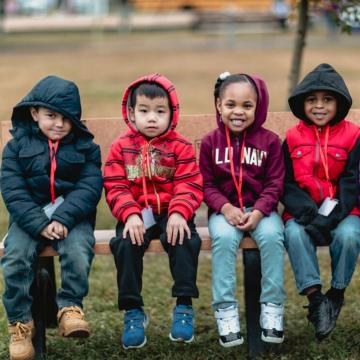 Four kids wearing coats as they experience the interactive fund of a Born Learning Trail outside Richmond, Virginia