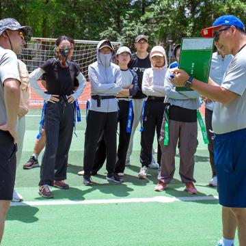 A flag football coach holds a clipboard explaining a play as part of a United Way Worldwide initative to improve youth fitness in China
