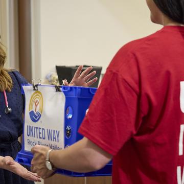 United Way volunteer hands a United Way-branded bag to a smiling woman