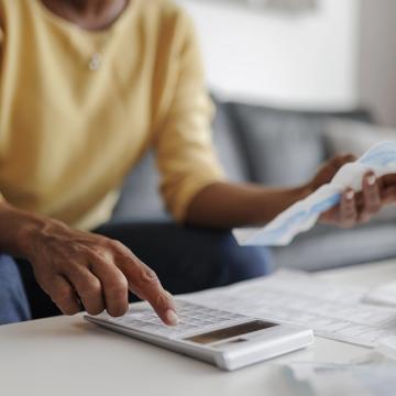 A person holds a bill and types into a calculator