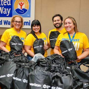 United Way Miami staff hold up Verizon emergency preparedness kits offered as part of the United We Prepare initiative