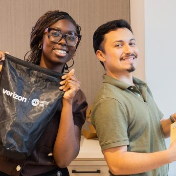 A woman holds up an emergency kit and a man holds preparedness materials
