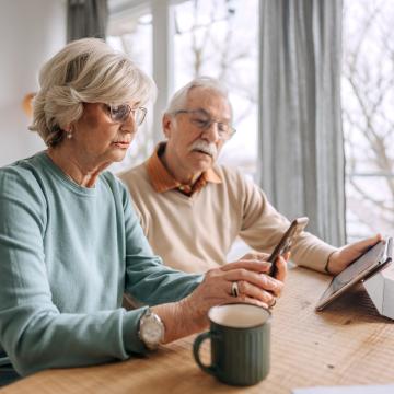 Two people looking at a phone and siting at a table. 
