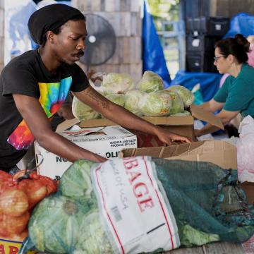 People peruse onions, cabbages and other vegetables at a farmer's market. 