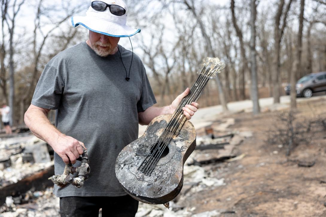 Man holding a burned up guitar