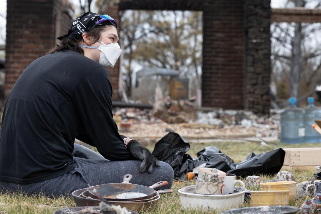 Adult sitting on the ground around debris