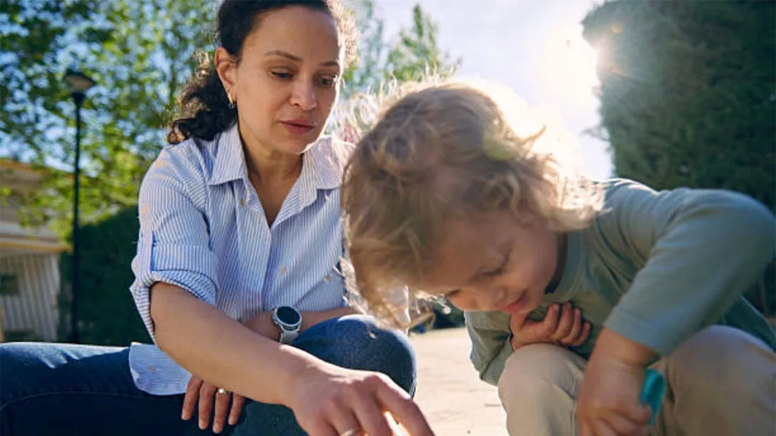 A woman plays with a child on a sunny day